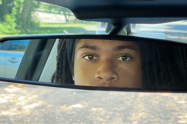 teen looking in the rear view mirror in a car