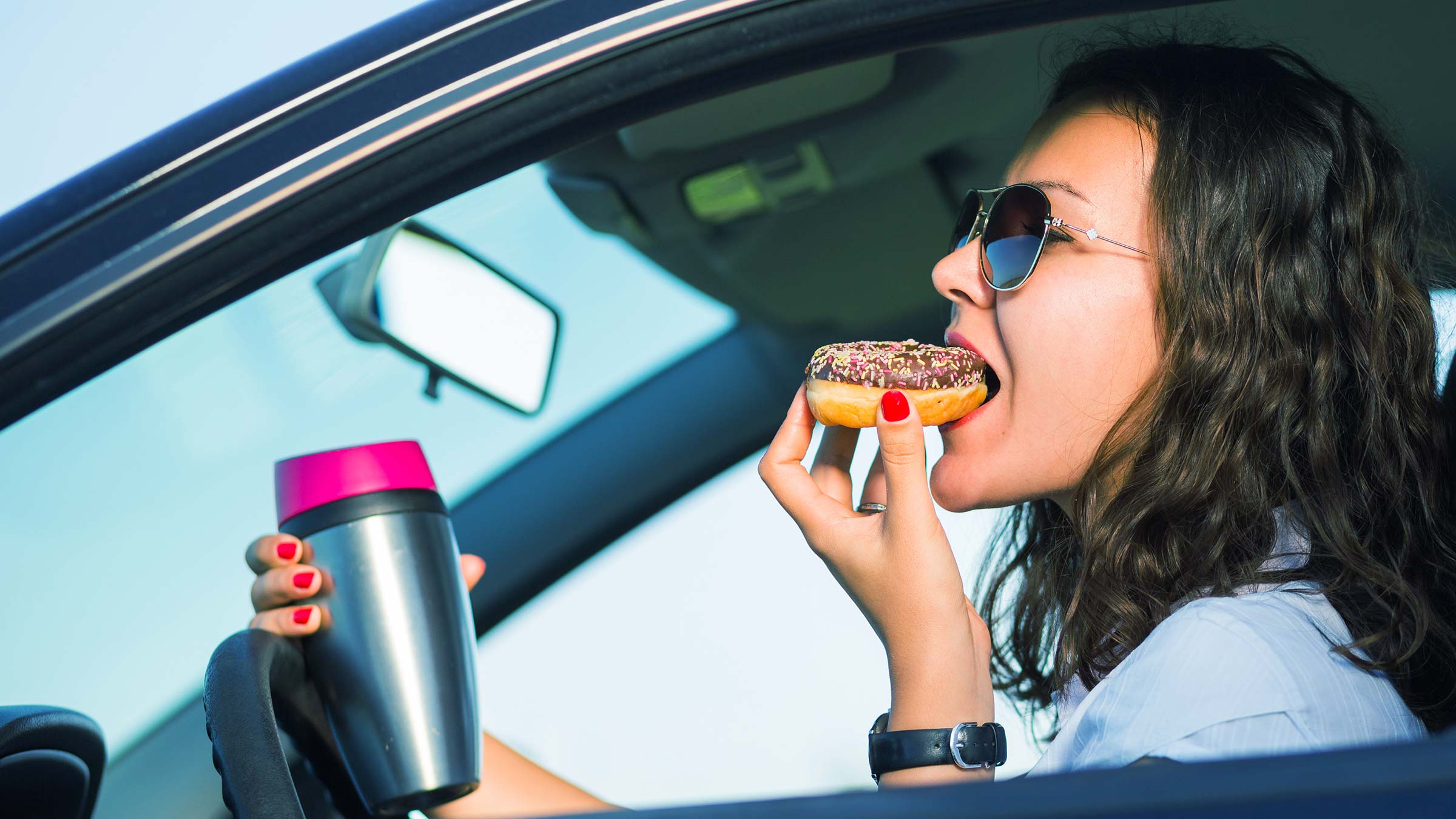 women eating and holding a water bottle while driving