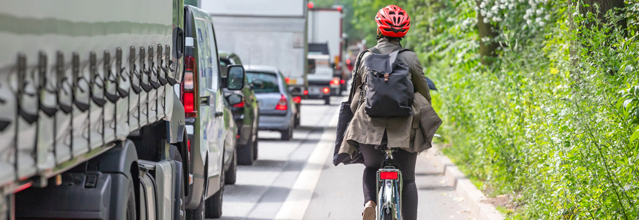 student on a bike next to cars back view