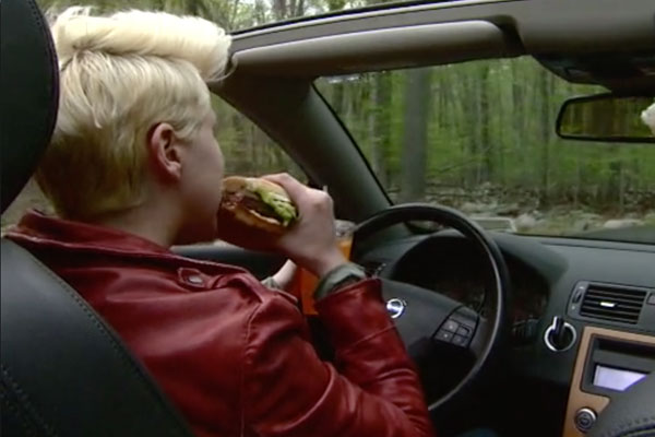 a back-view of a person driving and eating a sandwich