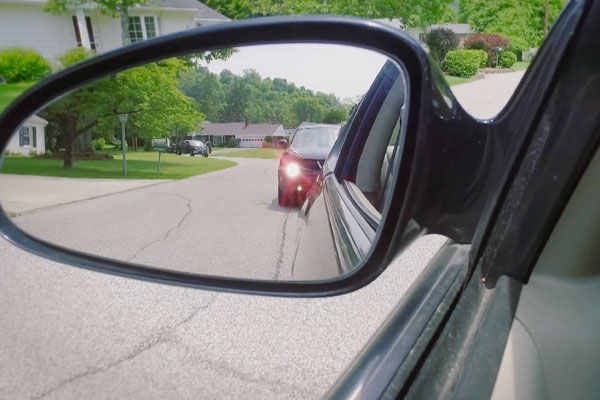 side mirror view of the car behind