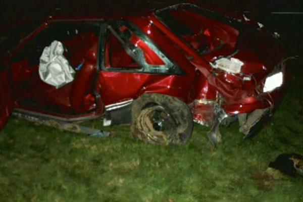 a destroyed red car on the grass after it crashed